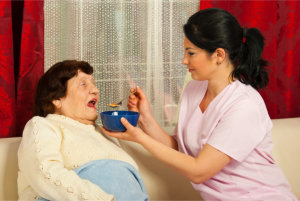 caregiver feeding elderly woman